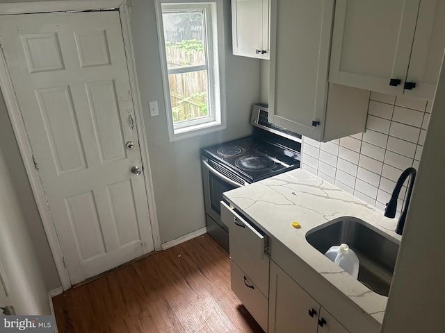 kitchen with backsplash, white cabinets, electric stove, and light stone countertops