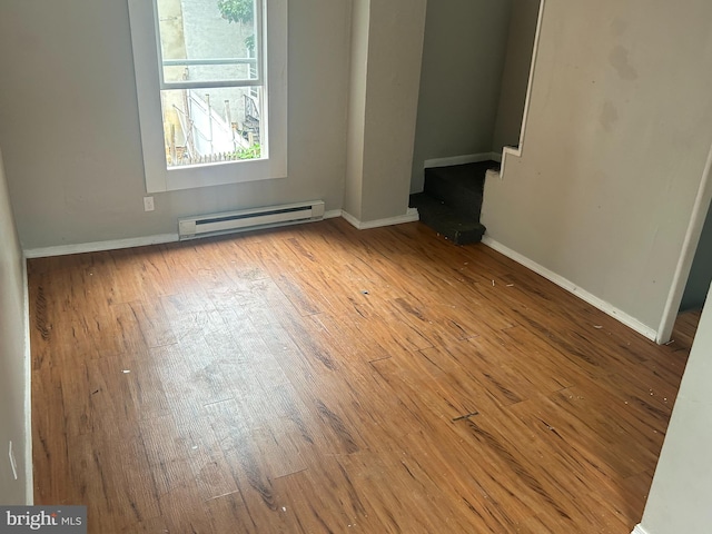 empty room with a baseboard radiator and light hardwood / wood-style floors