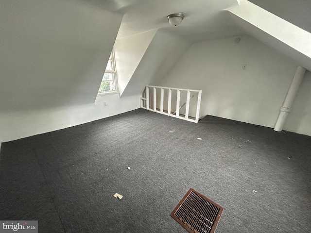 bonus room with vaulted ceiling with skylight and dark carpet