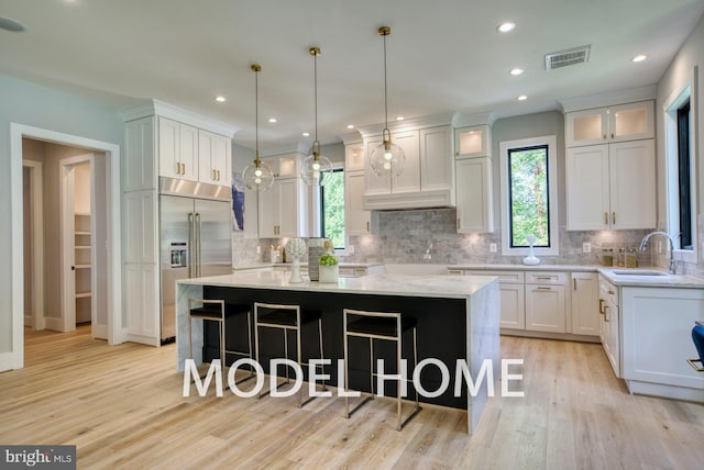 kitchen featuring a spacious island, plenty of natural light, sink, and built in fridge