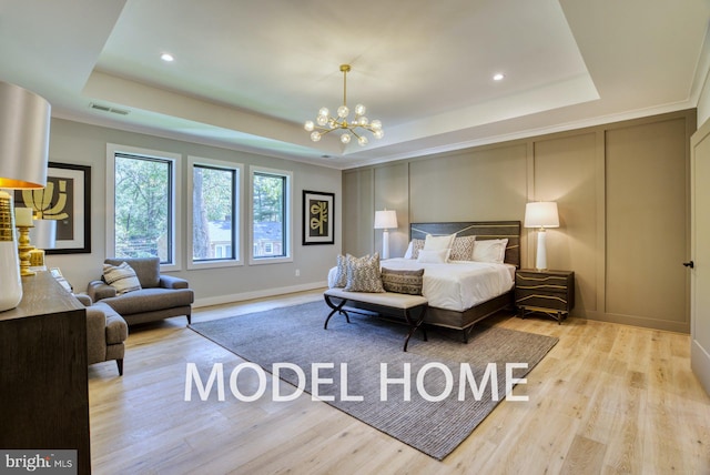 bedroom with light wood-type flooring, a tray ceiling, and a notable chandelier