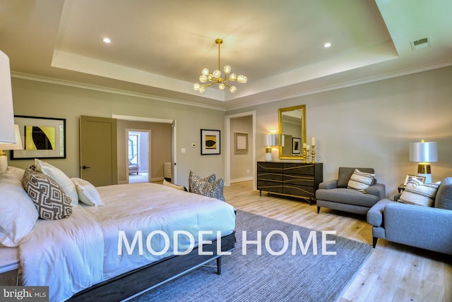 bedroom featuring crown molding, light hardwood / wood-style floors, a tray ceiling, and a chandelier