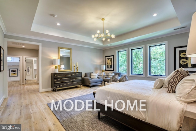 bedroom featuring ornamental molding, a tray ceiling, a chandelier, and light hardwood / wood-style floors