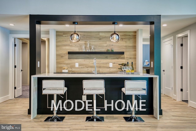 bar with sink, hanging light fixtures, and light hardwood / wood-style floors