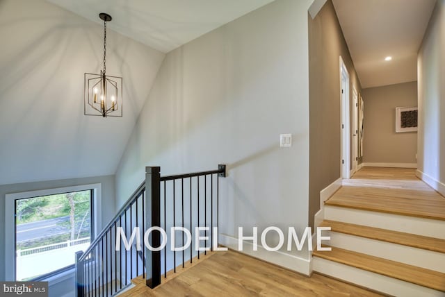 stairway with wood-type flooring, an inviting chandelier, and lofted ceiling