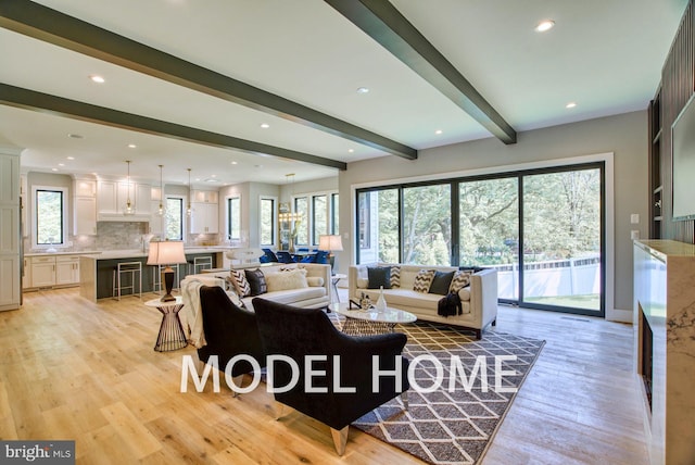 living room with light hardwood / wood-style flooring, beamed ceiling, and a healthy amount of sunlight