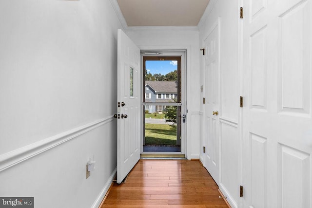 doorway with light hardwood / wood-style flooring and crown molding