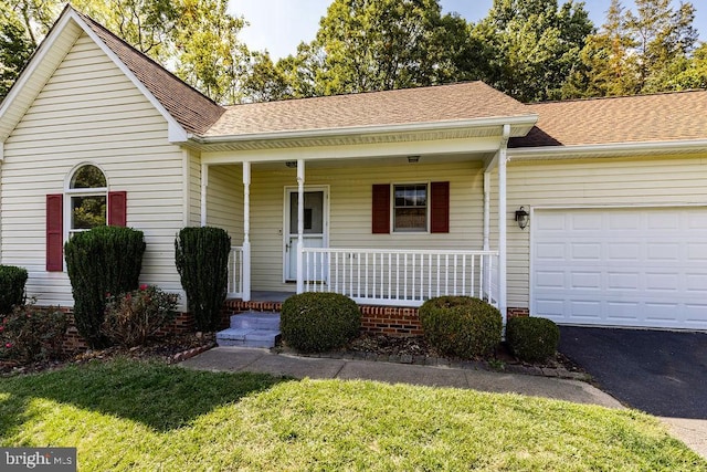 view of front of house with a front yard, a porch, and a garage