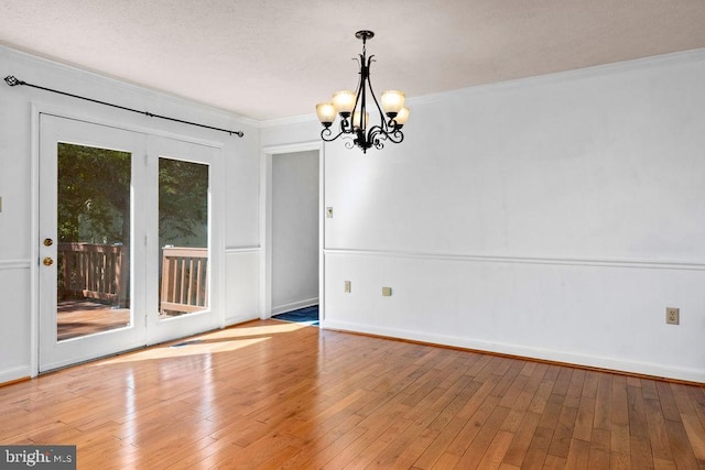 spare room featuring a textured ceiling, a chandelier, light hardwood / wood-style floors, and crown molding