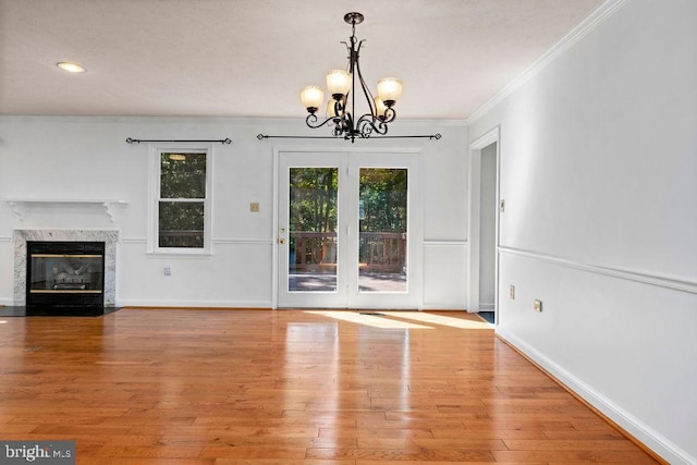 unfurnished living room featuring a chandelier, light hardwood / wood-style floors, a fireplace, and crown molding