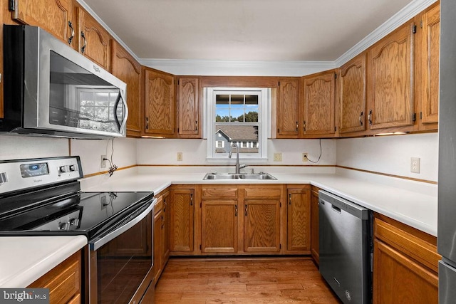 kitchen featuring appliances with stainless steel finishes, ornamental molding, sink, and light hardwood / wood-style flooring