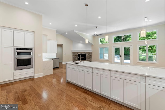 kitchen featuring stainless steel appliances, sink, white cabinets, and decorative light fixtures