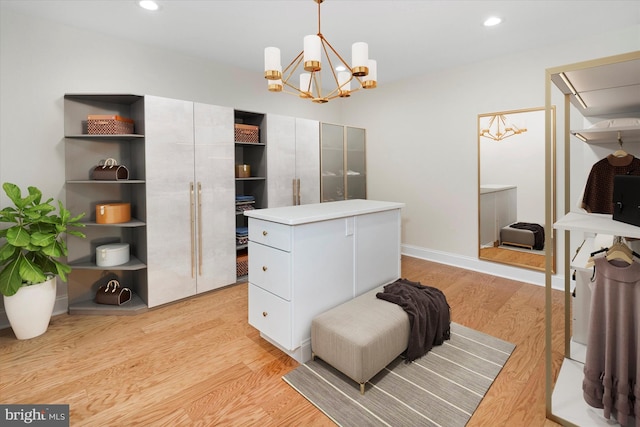 walk in closet featuring light hardwood / wood-style floors and a notable chandelier