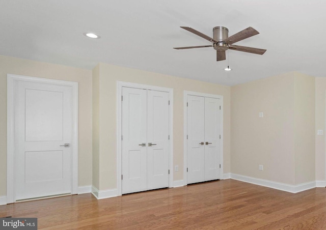 unfurnished bedroom featuring multiple closets, ceiling fan, and light wood-type flooring