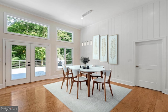 dining space with ornamental molding, light wood-type flooring, and french doors