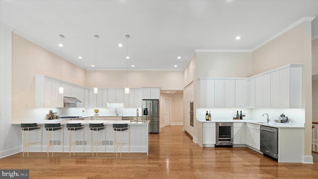 kitchen with wine cooler, a kitchen bar, appliances with stainless steel finishes, white cabinets, and a high ceiling