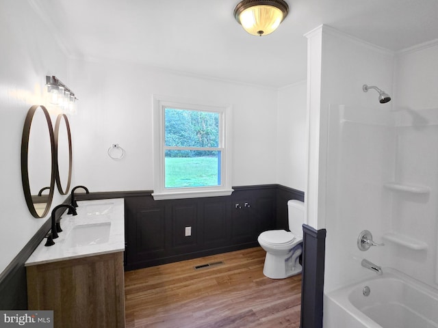 full bathroom featuring wood-type flooring, ornamental molding, shower / bathing tub combination, vanity, and toilet