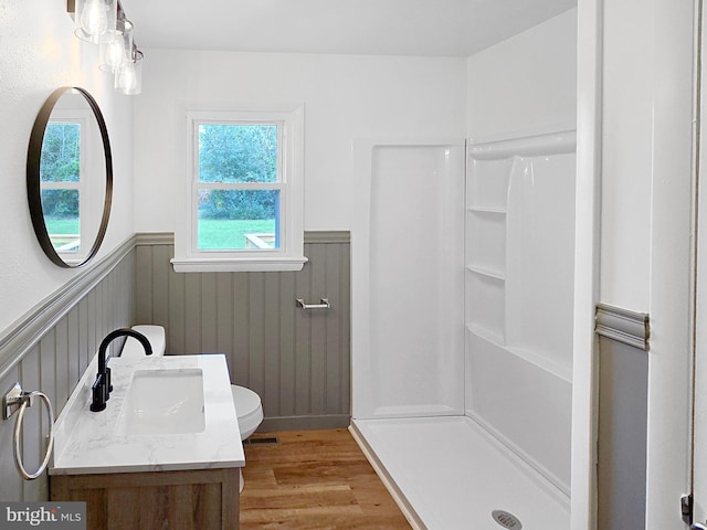 bathroom with a shower, vanity, toilet, and hardwood / wood-style flooring