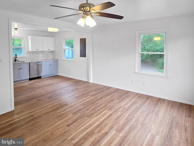 unfurnished living room with ceiling fan, electric panel, light hardwood / wood-style floors, and a wealth of natural light