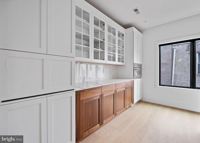 706 Latona St Unit F, Philadelphia, PA 19147 - kitchen with light wood finished floors, glass insert cabinets, oven, light stone counters, and white cabinets