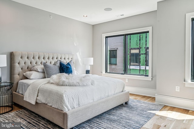 bedroom with wood-type flooring and multiple windows