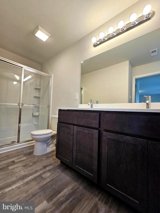 bathroom featuring hardwood / wood-style floors, a shower with door, vanity, and toilet