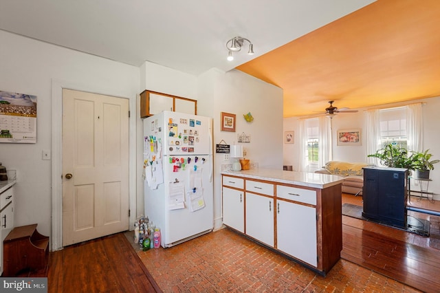 kitchen featuring white fridge, hardwood / wood-style flooring, white cabinetry, and kitchen peninsula