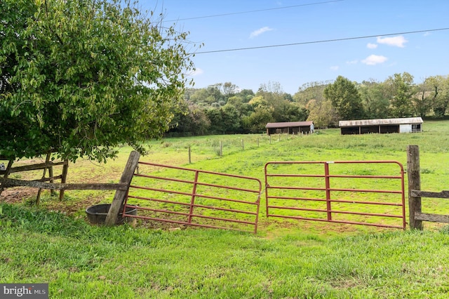 view of gate featuring a lawn and a rural view