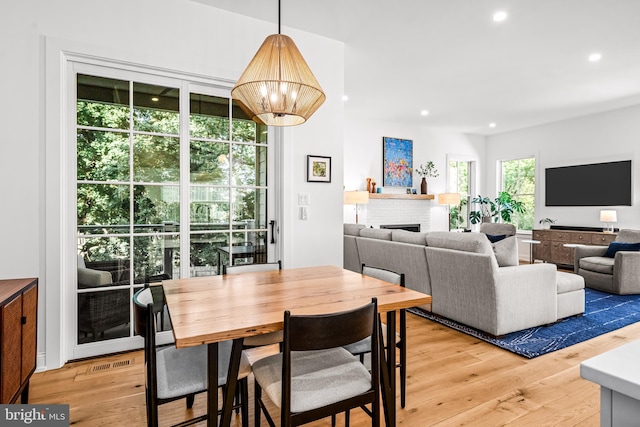 dining space with wood-type flooring, an inviting chandelier, and a fireplace