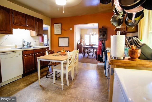 kitchen featuring hanging light fixtures, sink, white dishwasher, and a notable chandelier