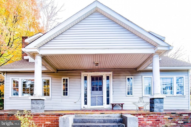 exterior space featuring a porch and roof with shingles