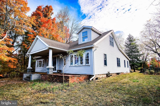 view of front of house with a porch, roof with shingles, and a front yard