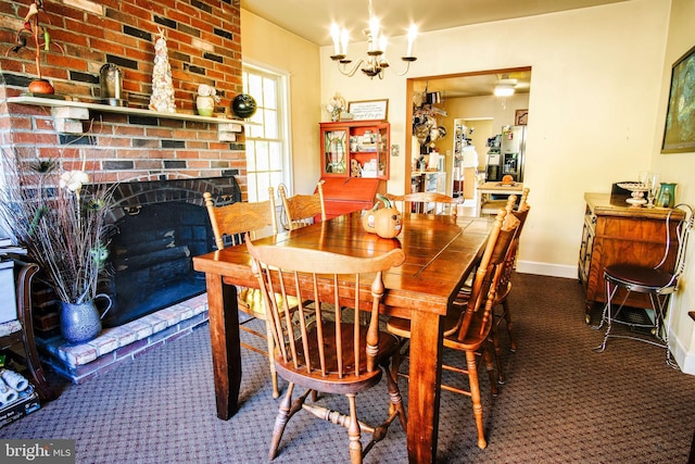 dining space featuring a chandelier, a brick fireplace, baseboards, and carpet