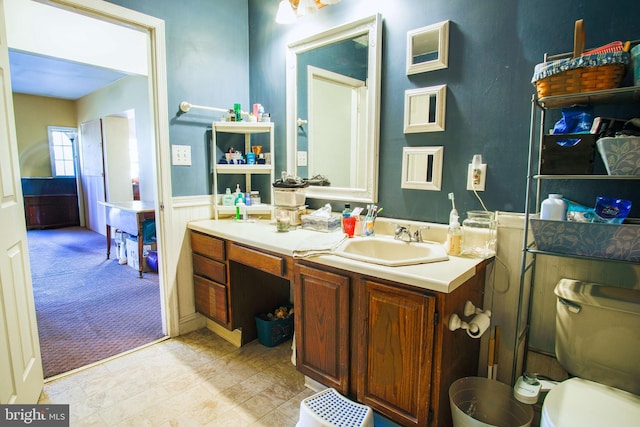 bathroom with toilet, vanity, and wainscoting