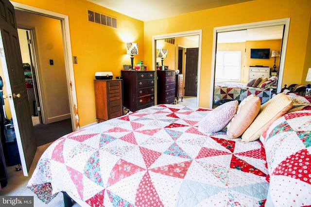 bedroom featuring visible vents, baseboards, two closets, and carpet floors