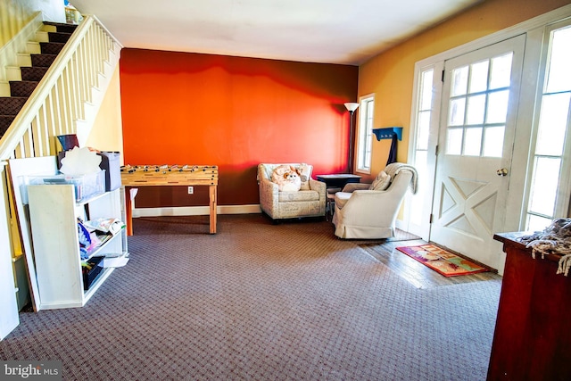sitting room featuring carpet flooring, baseboards, and stairs
