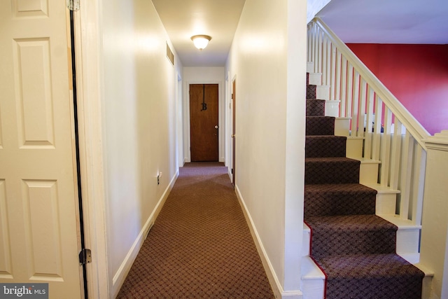 hallway featuring carpet flooring, baseboards, visible vents, and stairway