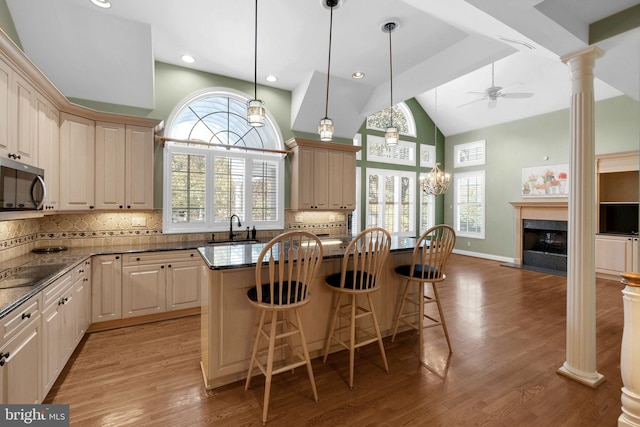 kitchen with a kitchen bar, a center island, a healthy amount of sunlight, and decorative columns