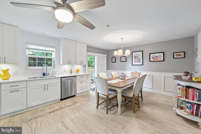 kitchen featuring a healthy amount of sunlight, ceiling fan with notable chandelier, stainless steel dishwasher, and white cabinetry