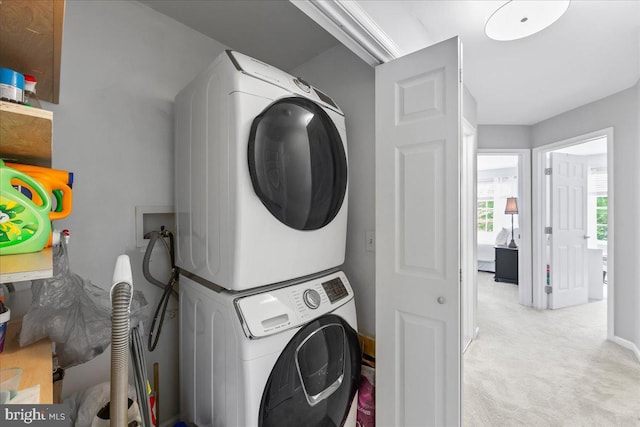 clothes washing area with stacked washer and dryer and light carpet