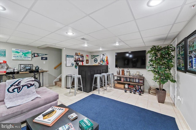 living room with a drop ceiling and tile patterned floors