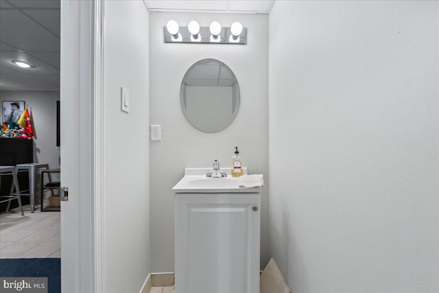 bathroom with a drop ceiling, vanity, and tile patterned floors