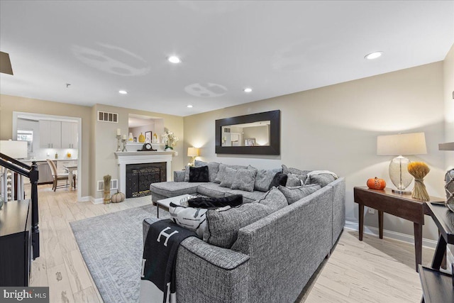 living room with light hardwood / wood-style flooring and a high end fireplace