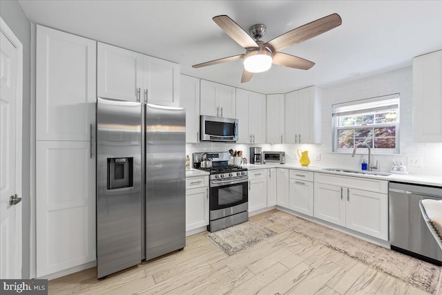 kitchen featuring sink, white cabinets, decorative backsplash, appliances with stainless steel finishes, and ceiling fan