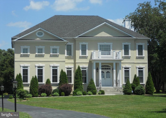 view of front facade featuring a balcony and a front lawn