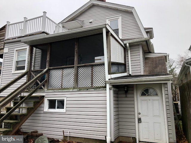 rear view of property featuring a balcony and a sunroom