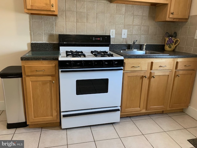 kitchen with white range, decorative backsplash, sink, and light tile patterned floors