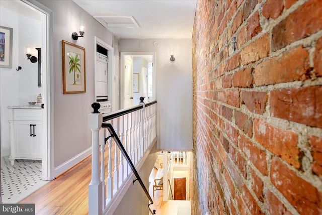 corridor featuring light hardwood / wood-style floors and brick wall