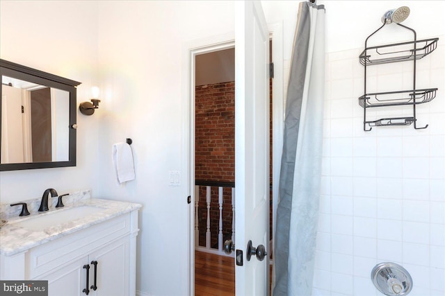 bathroom with walk in shower, vanity, and hardwood / wood-style floors