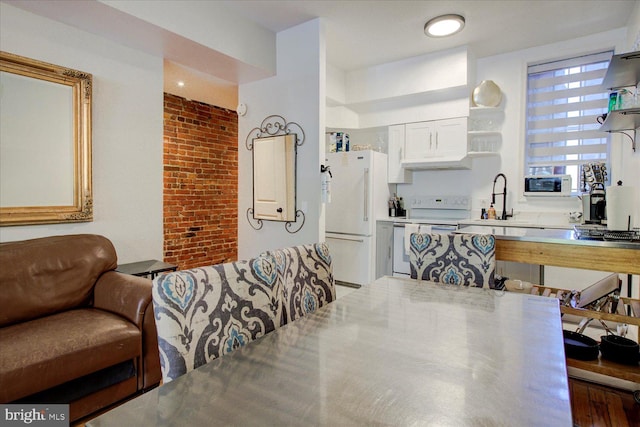 dining area with brick wall, hardwood / wood-style flooring, and sink